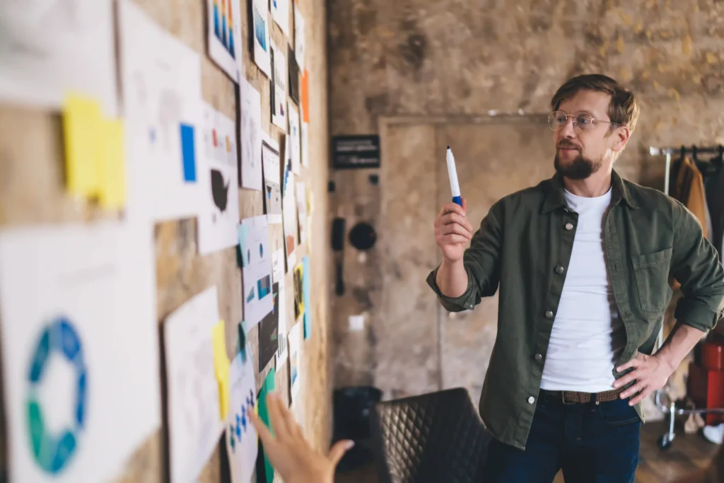 Startup team lead mapping rapid MVP plan on a wall of sketches and metrics.