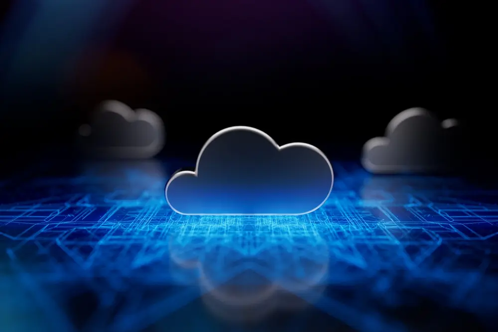A futuristic 3D illustration of a glowing blue cloud icon on a digital circuit background, with blurred cloud silhouettes in the distance.