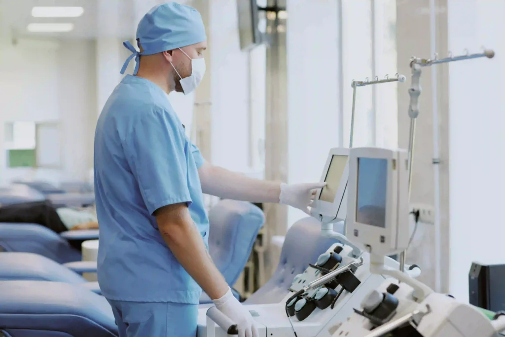 Healthcare worker operating dialysis machine in hospital clinic.
